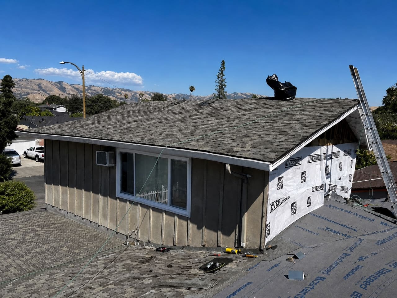 New underlayment and shingles being installed at a roof transition