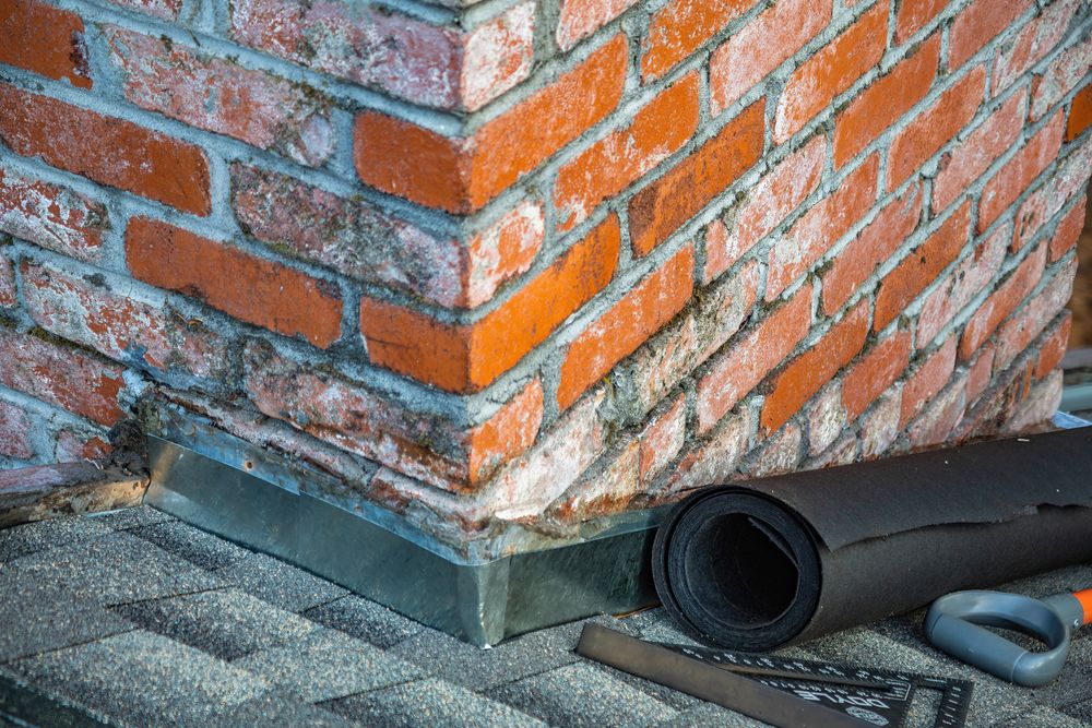 Metal flashing installed around the base of a brick chimney